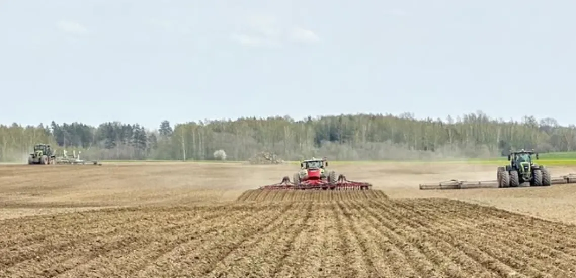 Trīs traktori lauka apstrādē